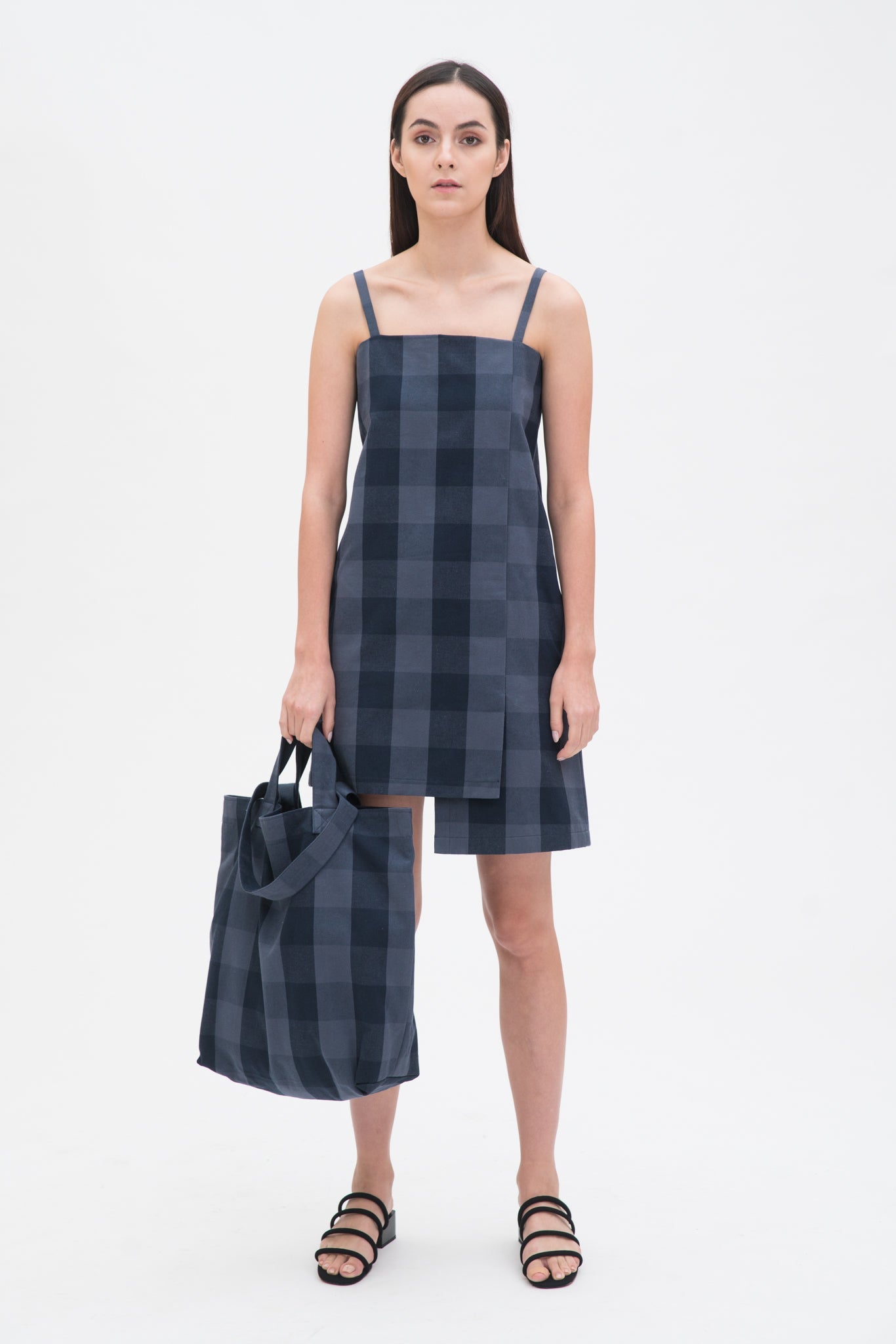 A woman in a blue checked dress is holding a blue checked tote bag