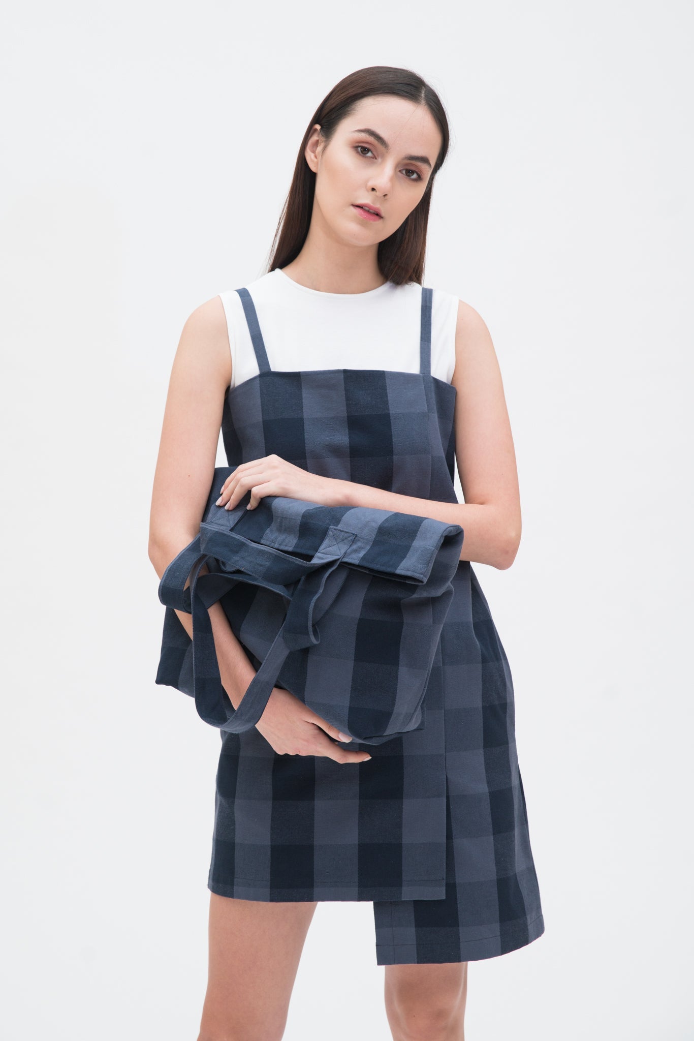 A woman in a blue checked dress is holding a blue checked tote bag