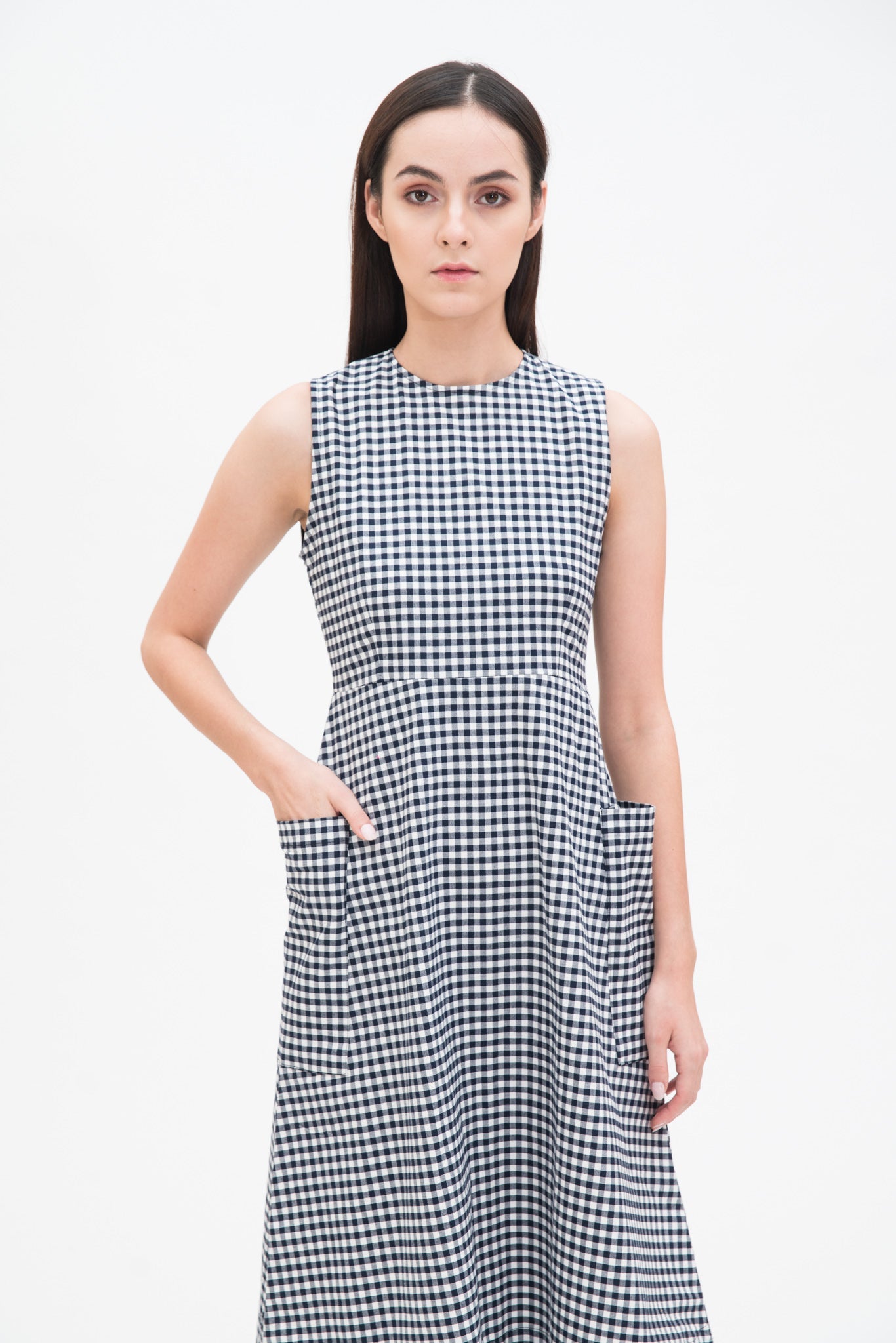 A woman with long dark hair is wearing a black and white checked dress.