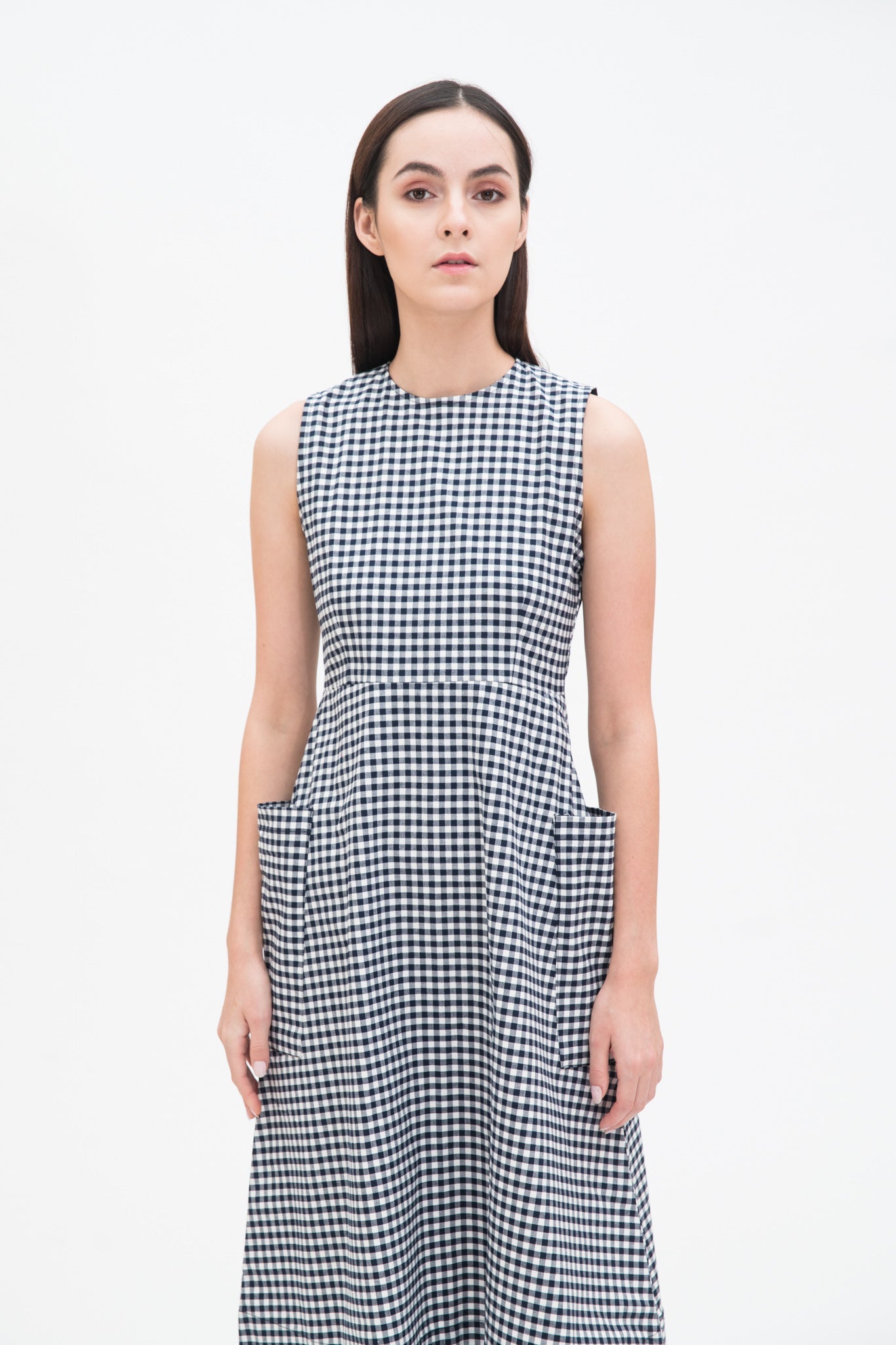 A woman with long dark hair is wearing a black and white checked dress.