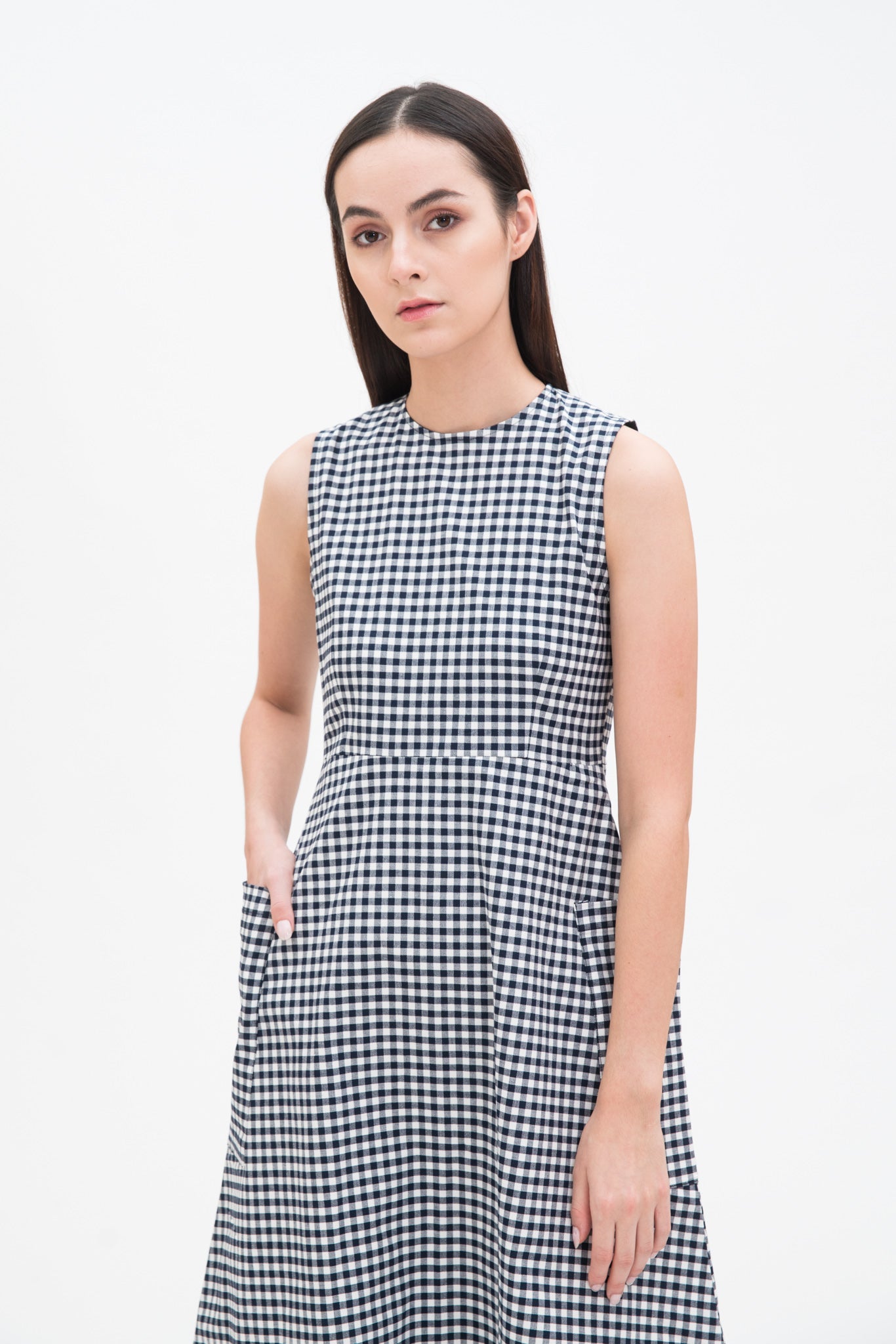 A woman with long dark hair is wearing a black and white checked dress.