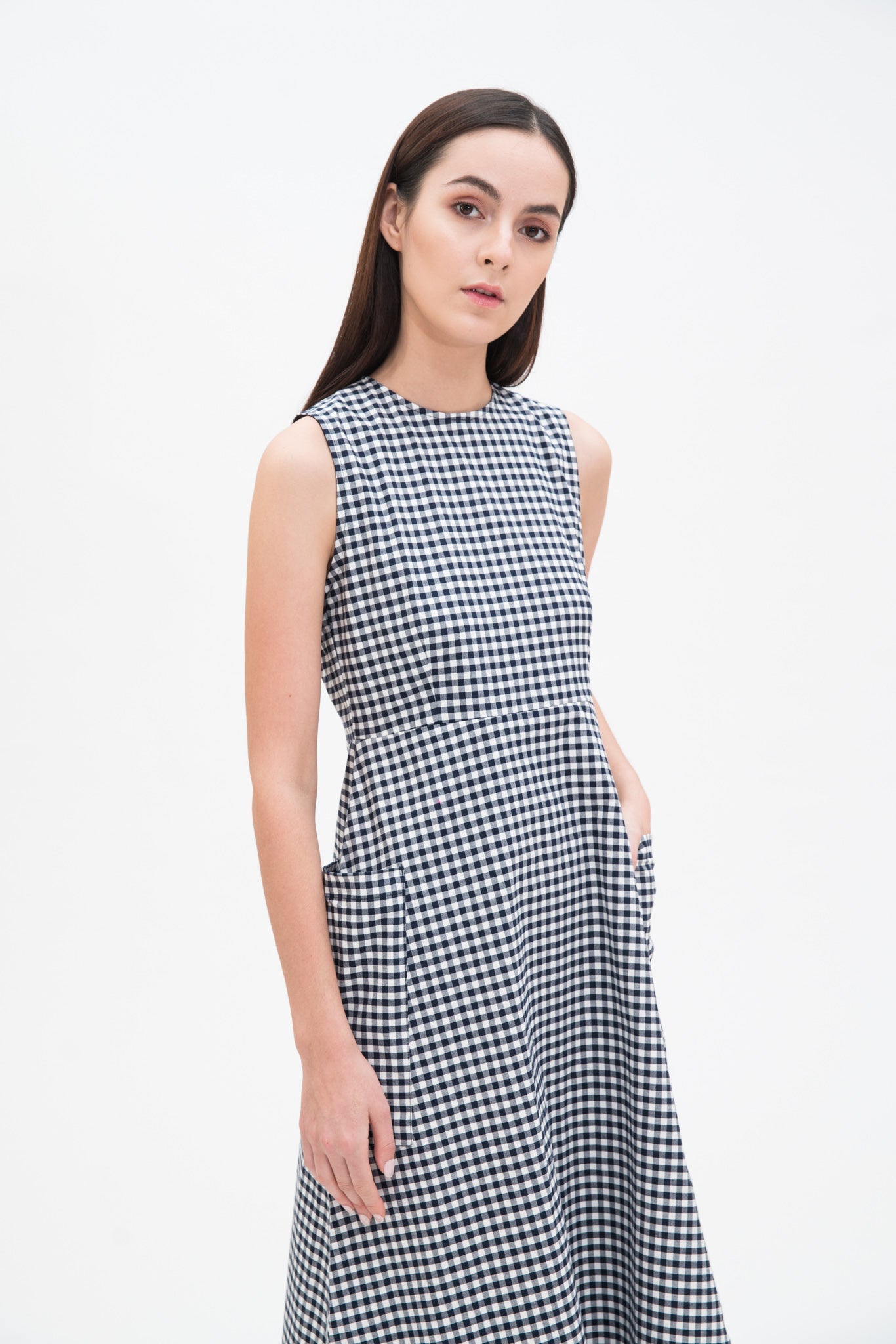 A woman with long dark hair is wearing a black and white checked dress.