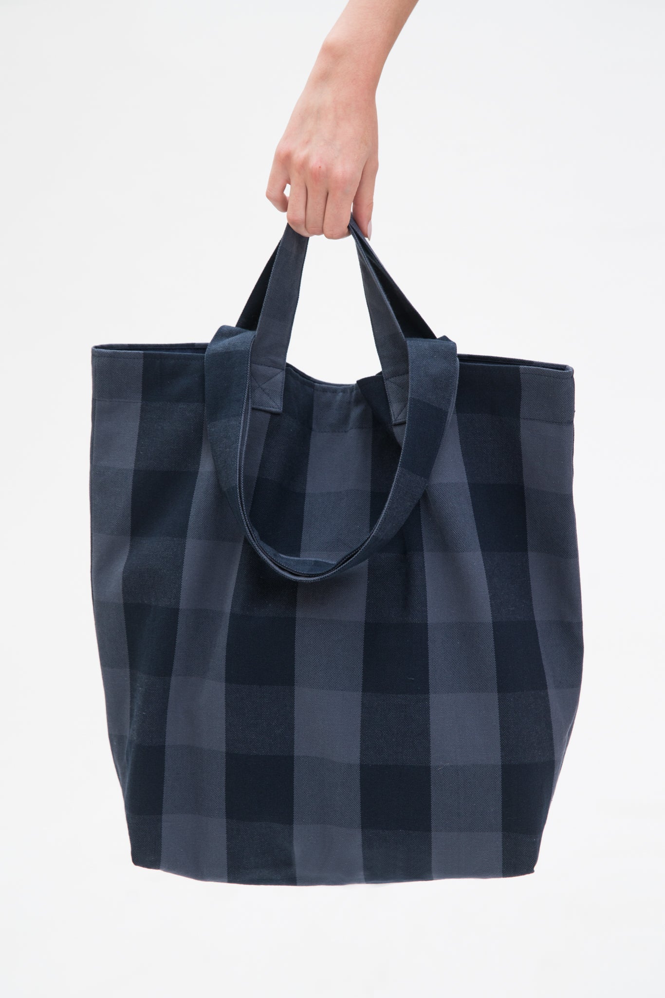 Someone holding a blue checked tote bag