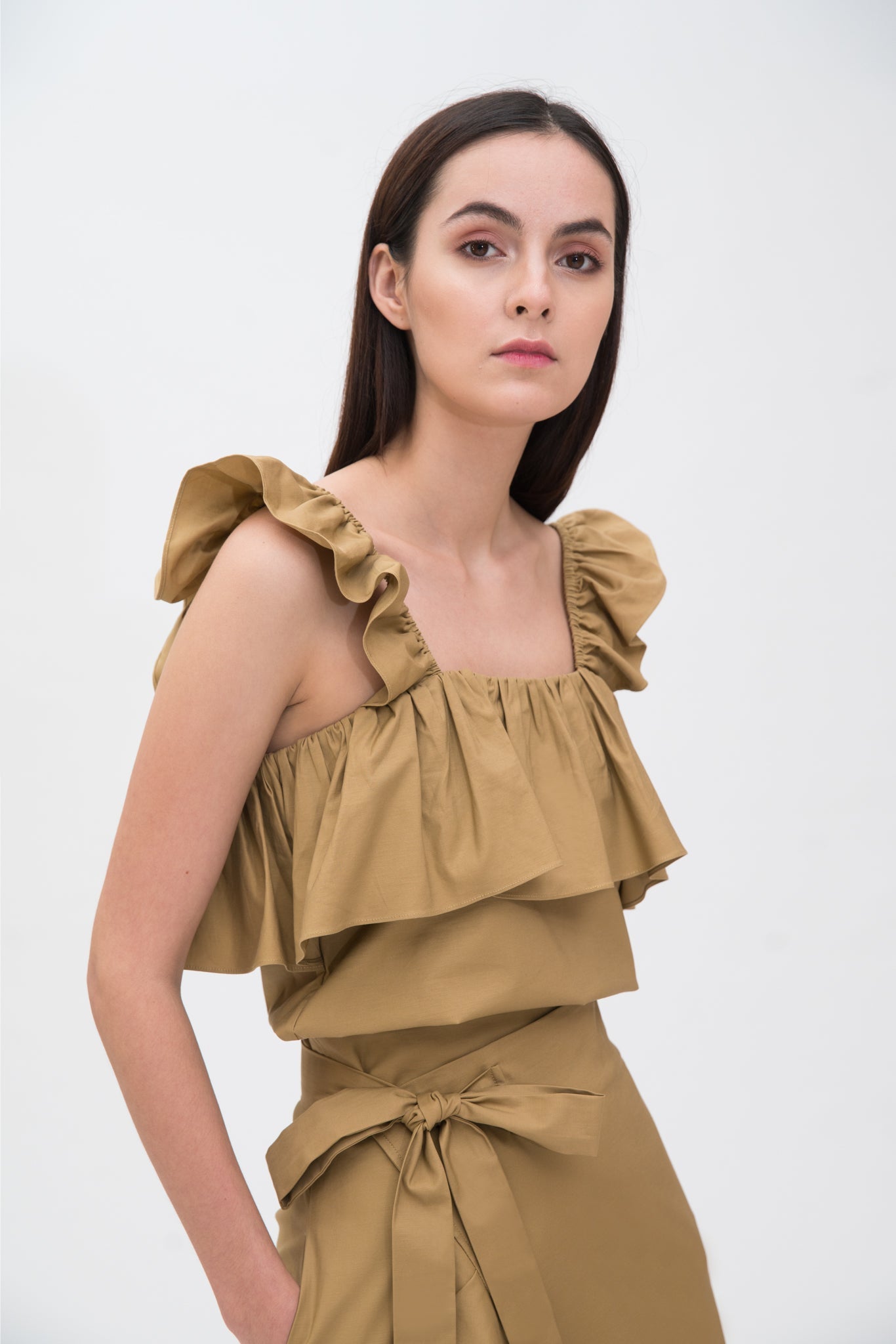 A woman is wearing a camel ruffled scrappy dress.