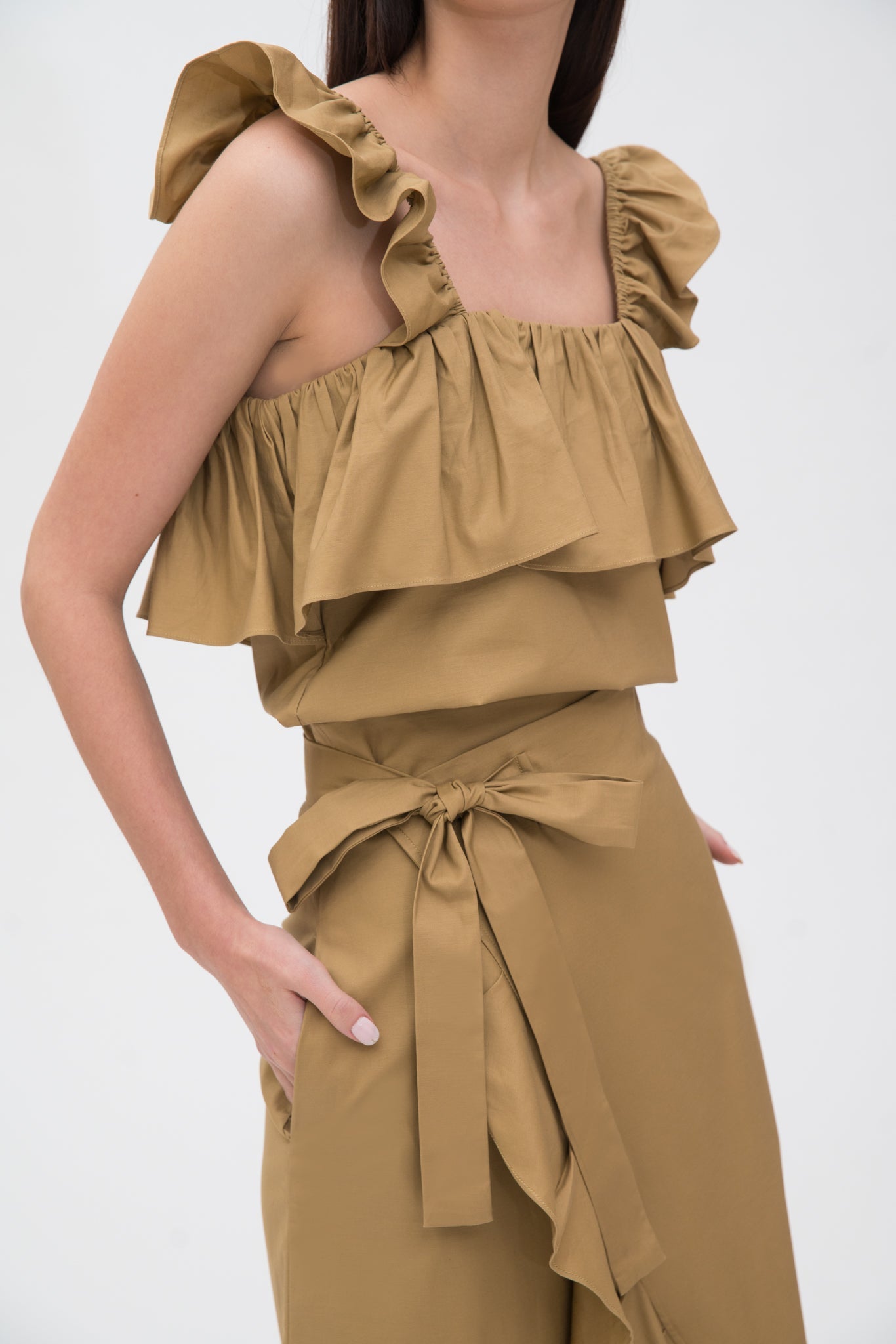 A woman is wearing a beige ruffled top and skirt.