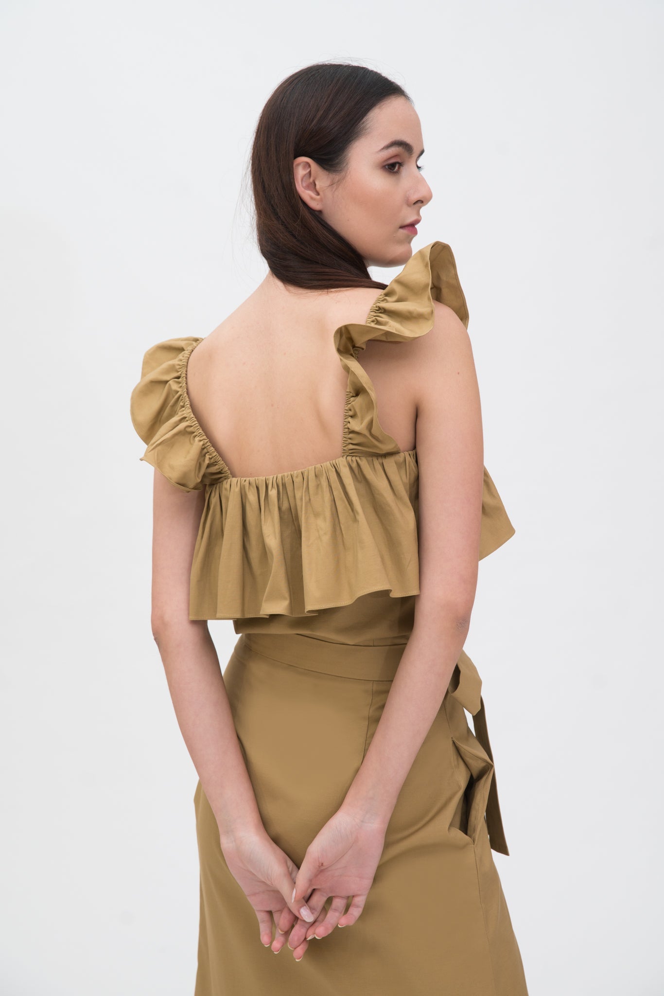 A woman is wearing a camel ruffled scrappy dress.