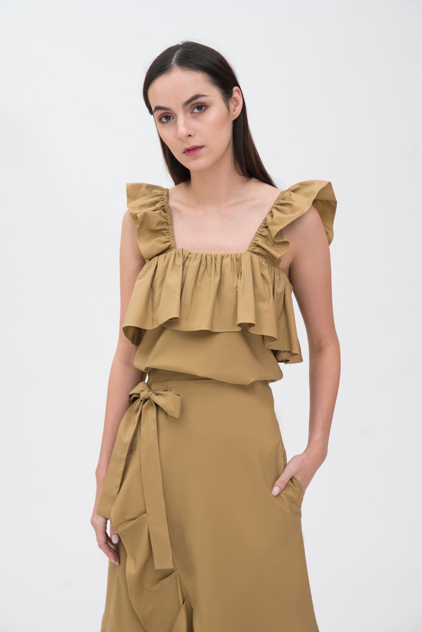 A woman is wearing a camel ruffled scrappy dress.