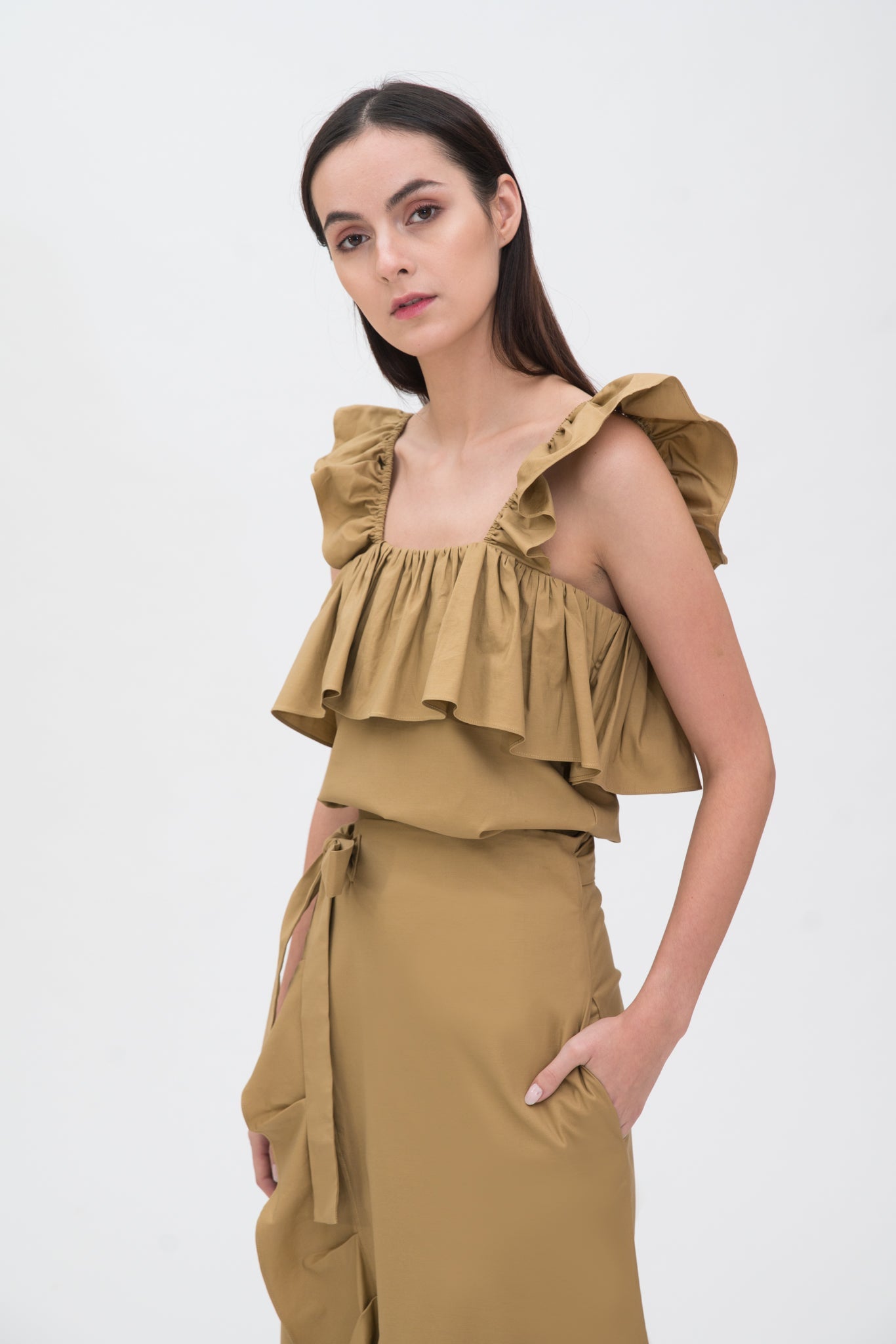 A woman is wearing a camel ruffled scrappy dress.