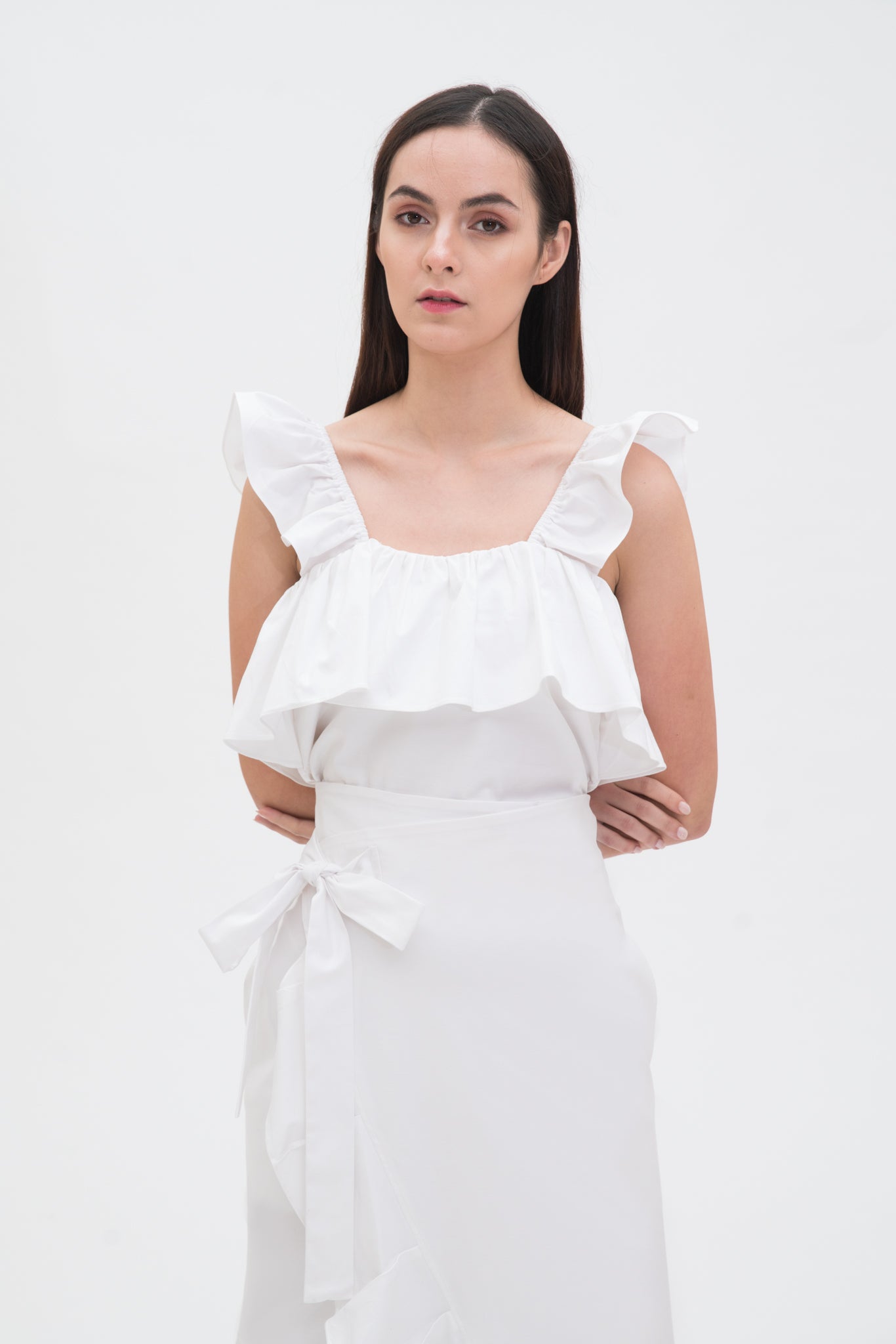 A woman is wearing a white ruffled top and skirt.
