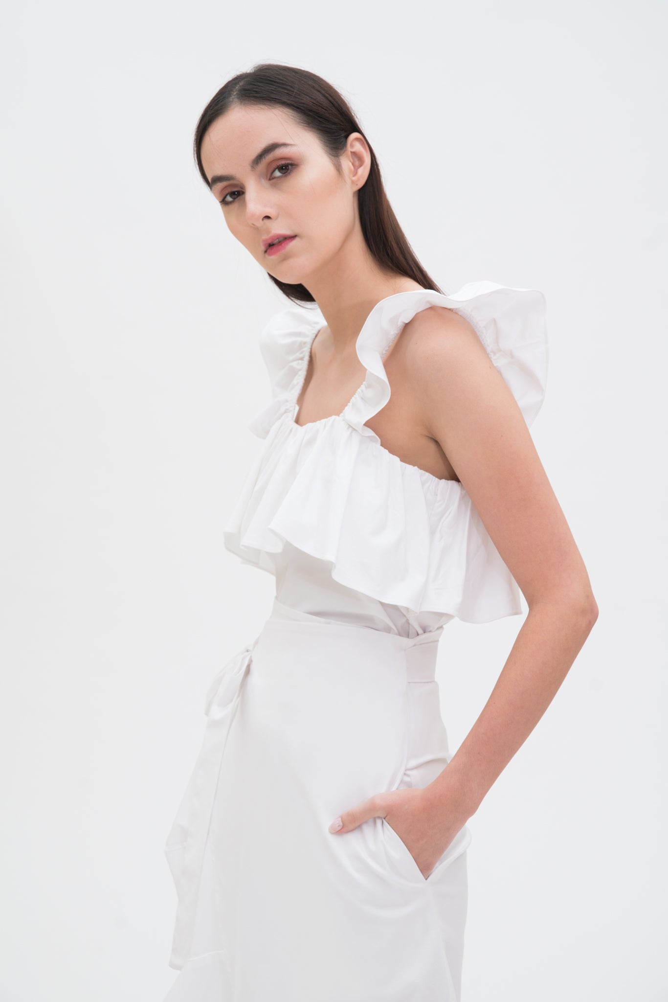 A woman is wearing a white ruffled scrappy dress.