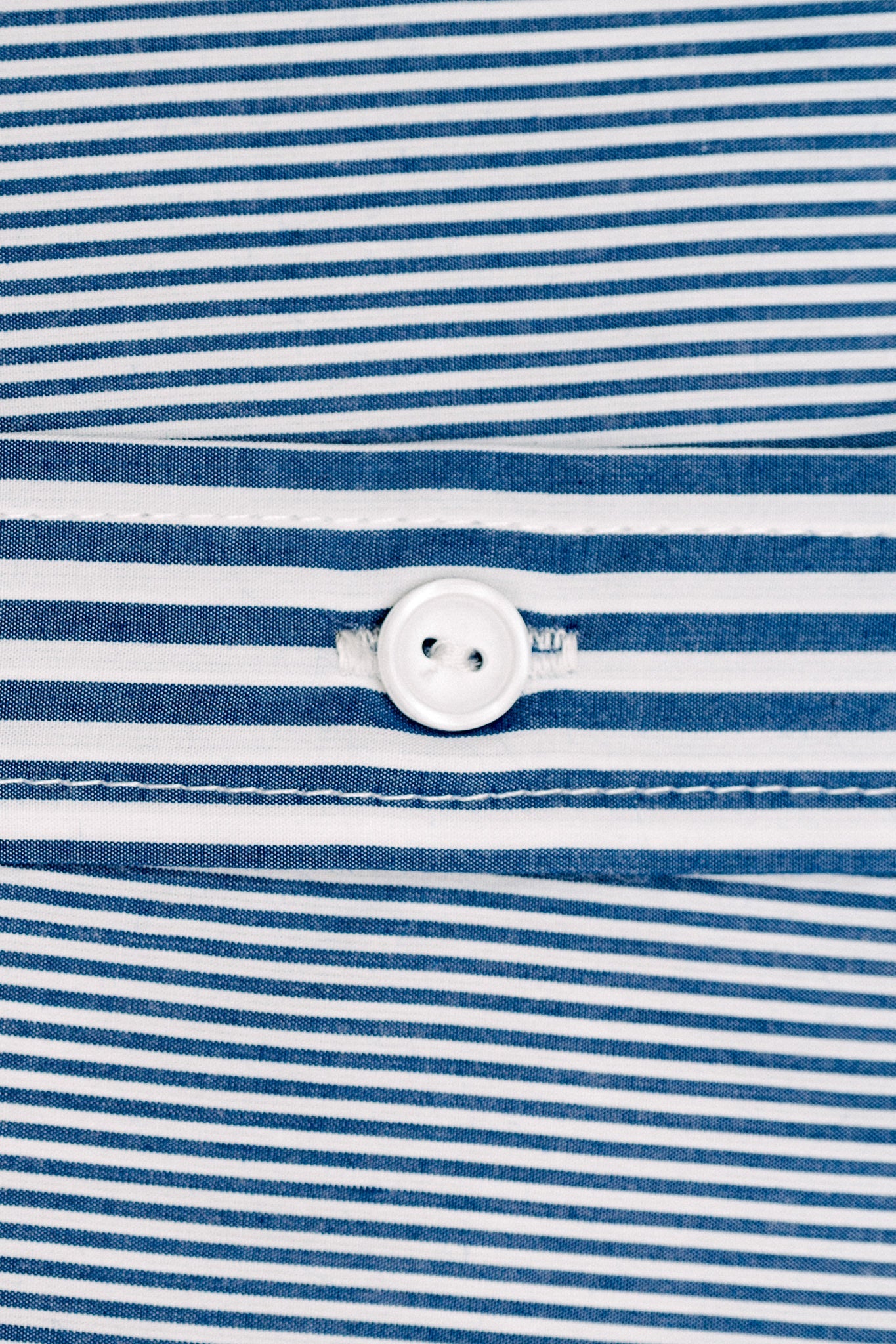 Closeup of blue and white striped material and a white button