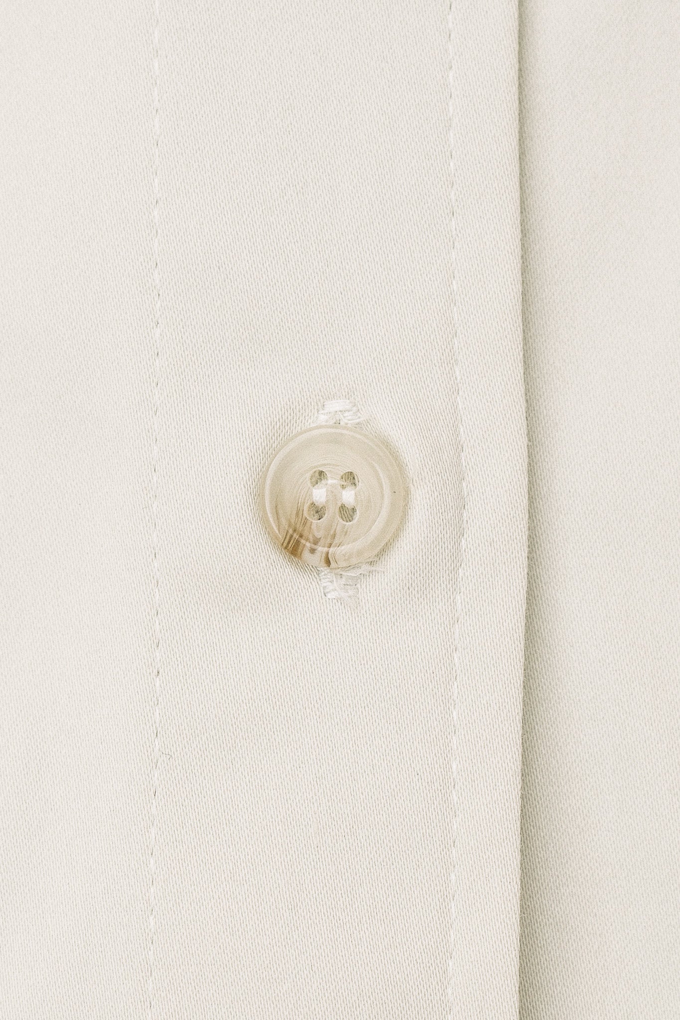 A close up of off-white material and a button