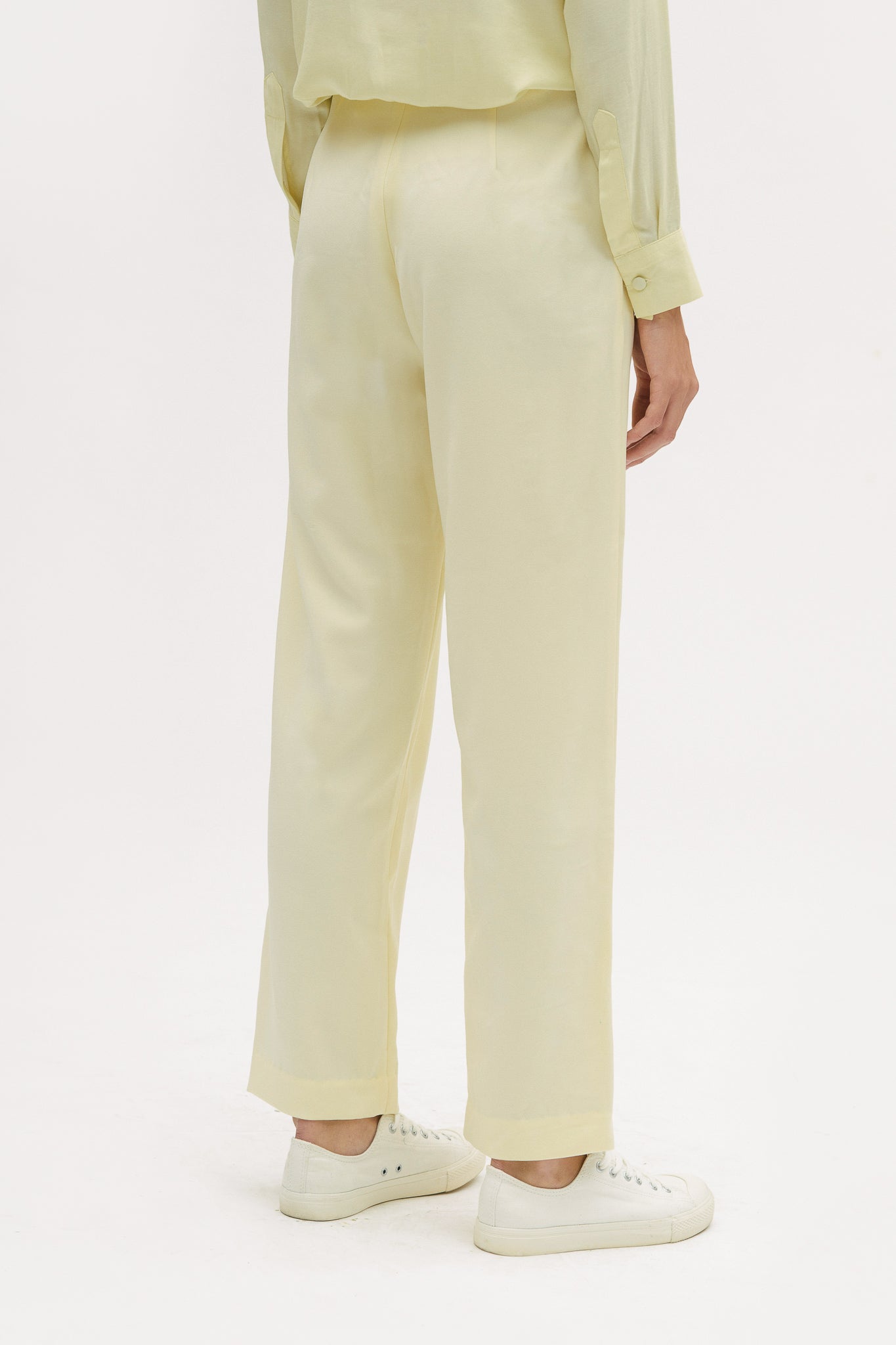A woman is wearing a yellow shirt and yellow trousers. She is also wearing white tennis shoes.