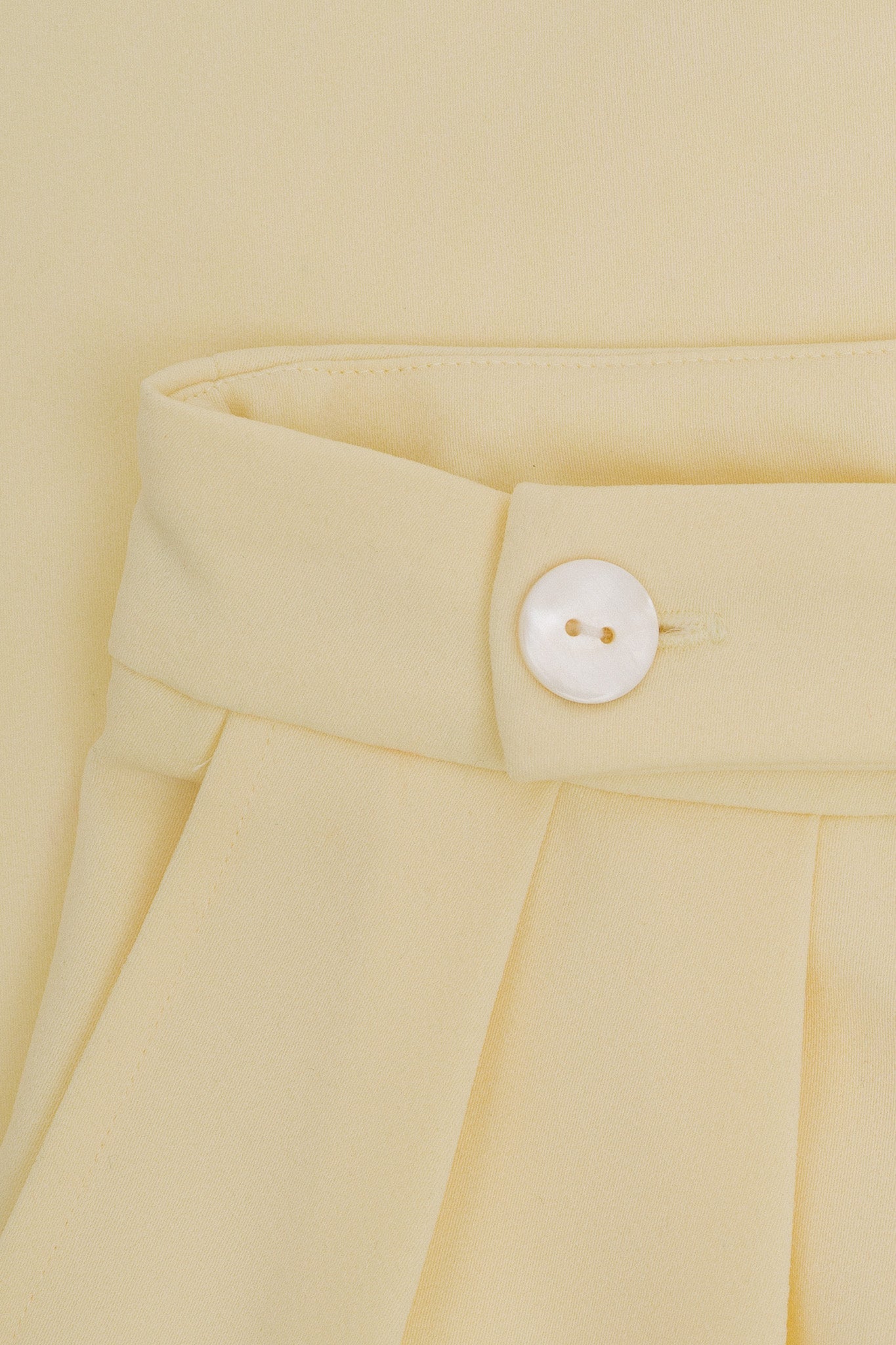 A close up of yellow fabric and a white button