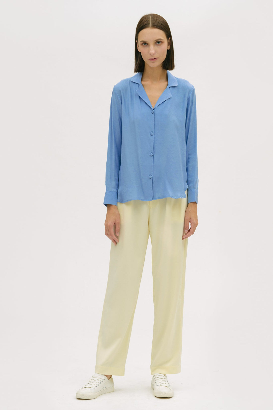 A woman is wearing a blue shirt and yellow trousers.