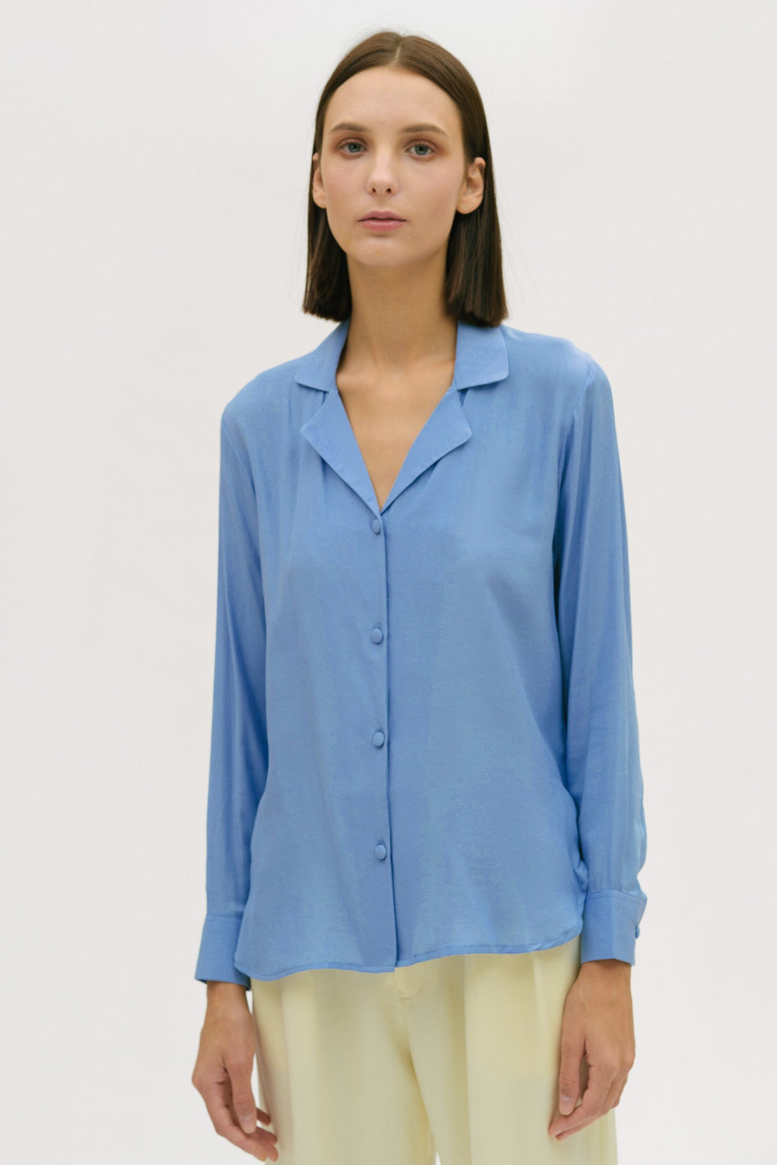 A woman is wearing a blue shirt and yellow trousers.