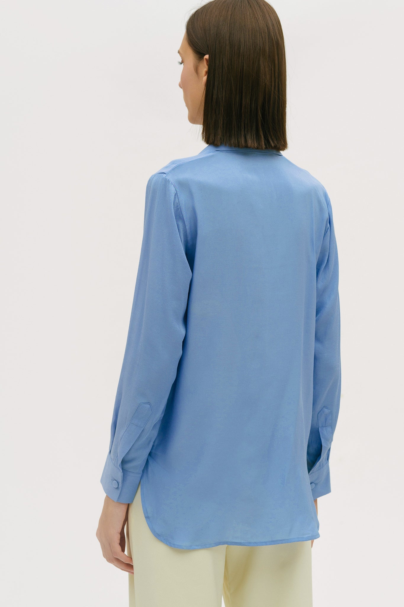 A woman is wearing a blue shirt and yellow trousers.