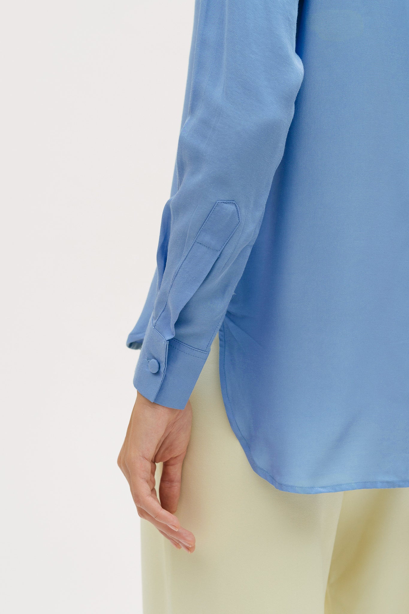A woman is wearing a blue shirt and yellow trousers.