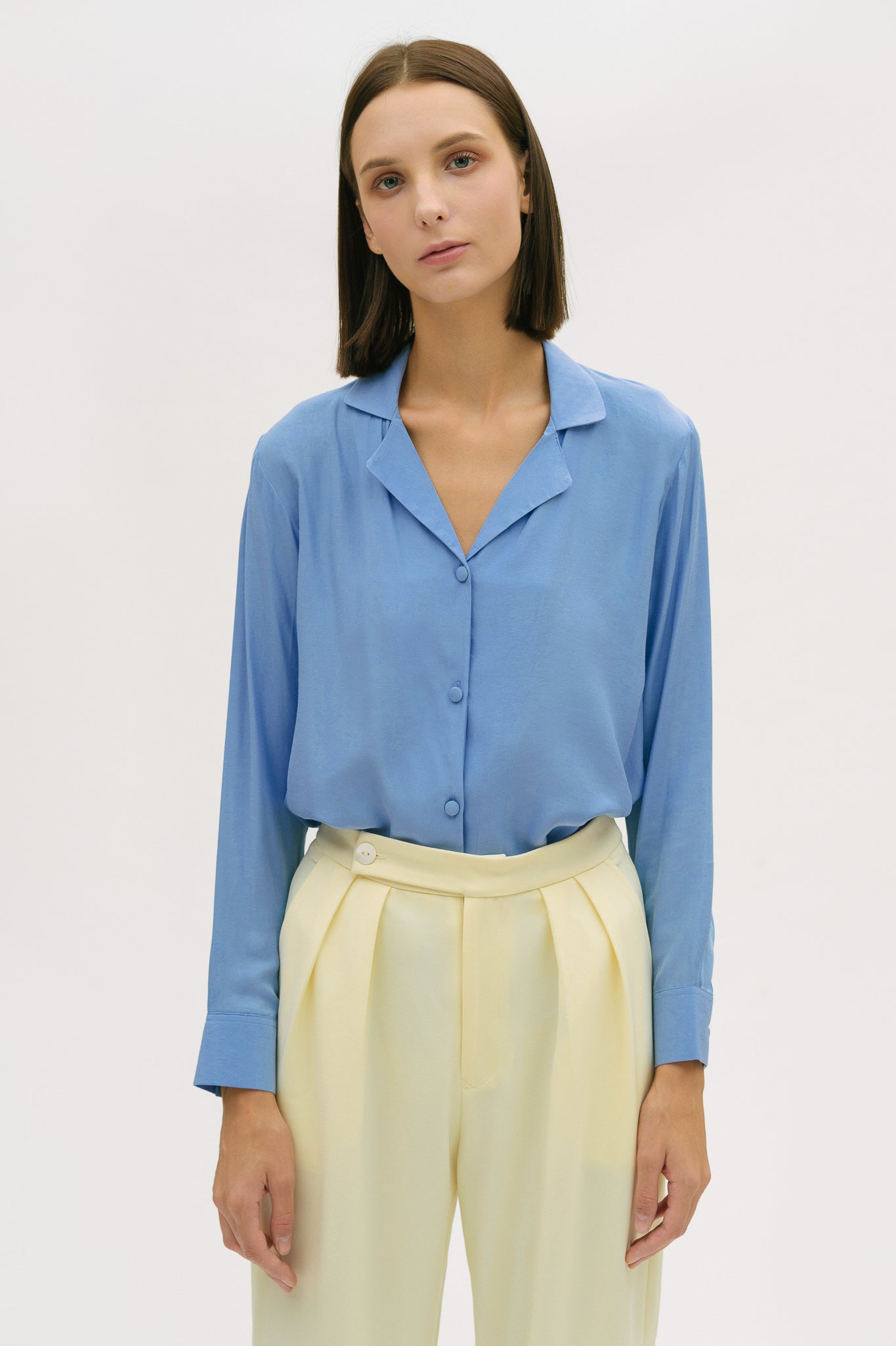 A woman is wearing a blue shirt and yellow trousers.