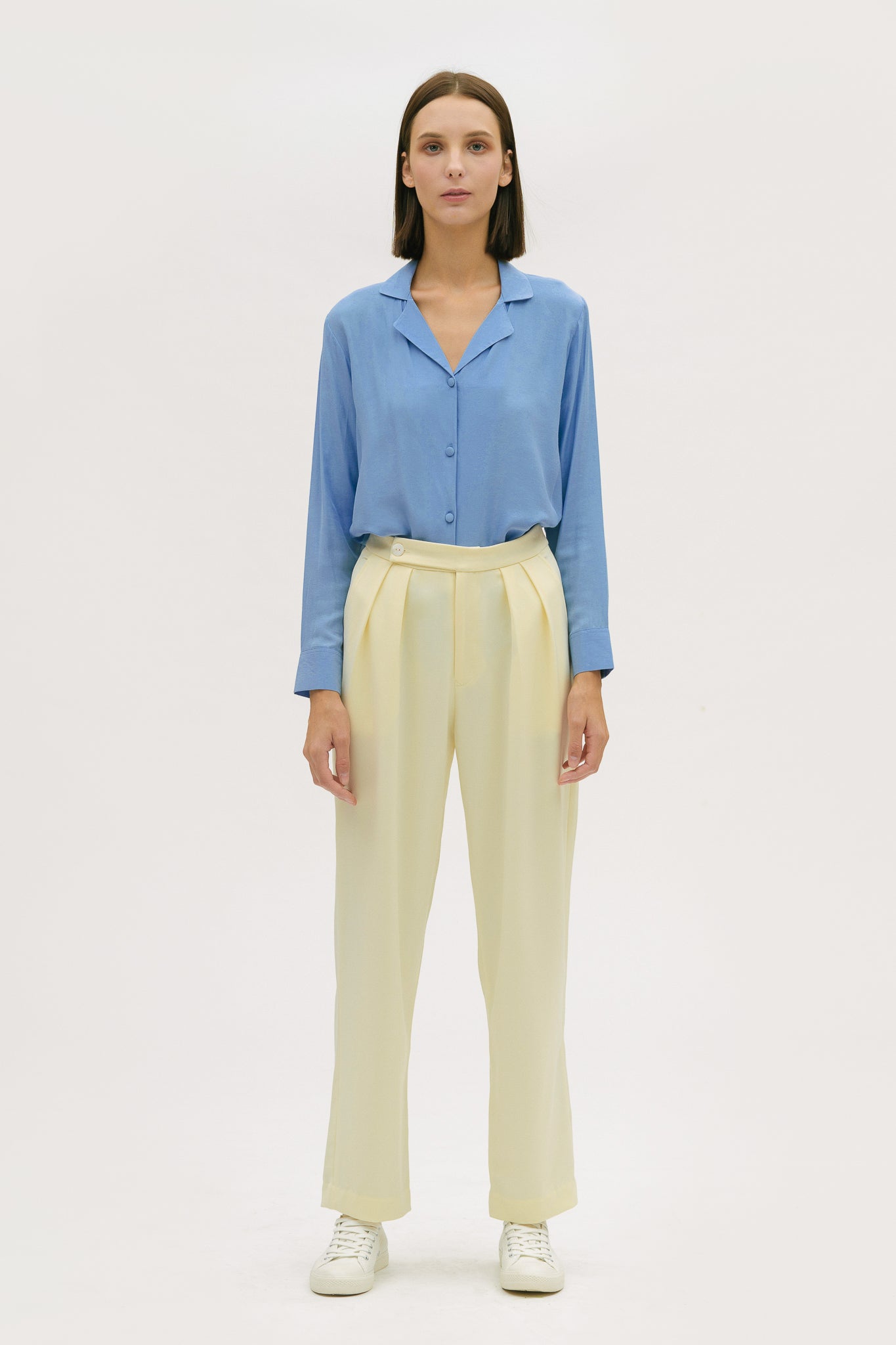 A woman is wearing a blue shirt and yellow trousers.