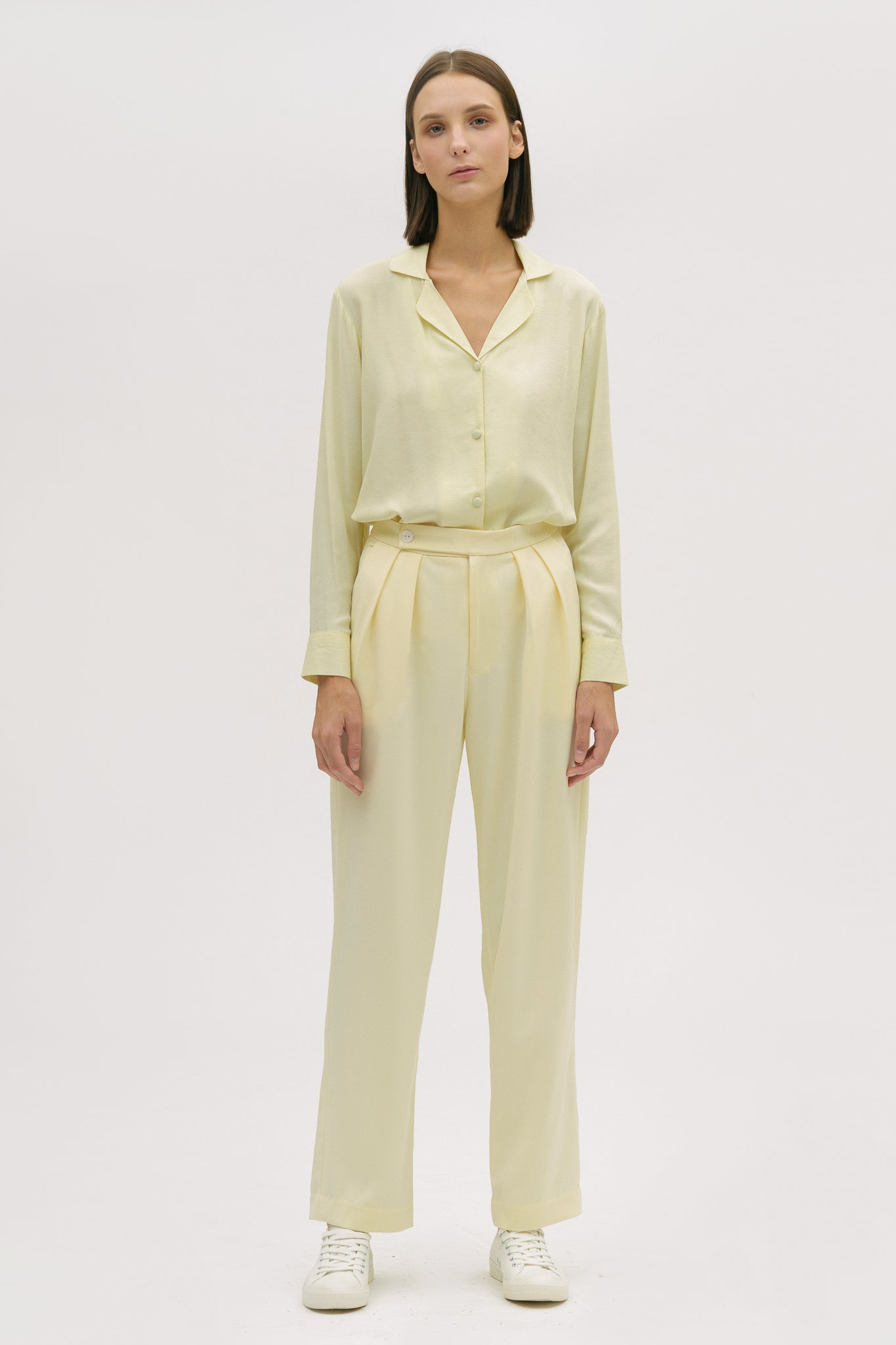 A woman is wearing a lightweight yellow shirt and trousers