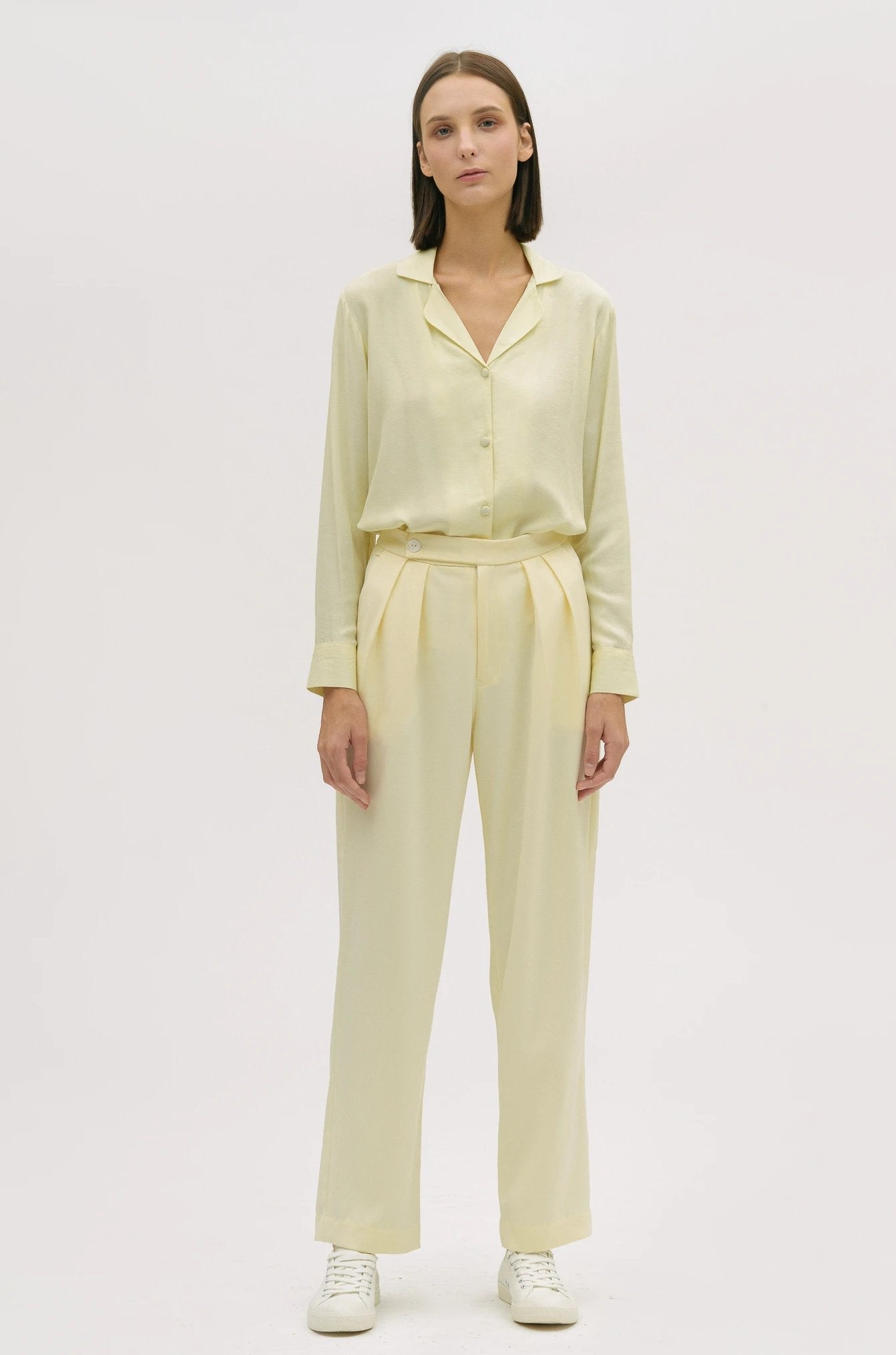 A woman is wearing a yellow shirt and yellow trousers. She is also wearing white tennis shoes.
