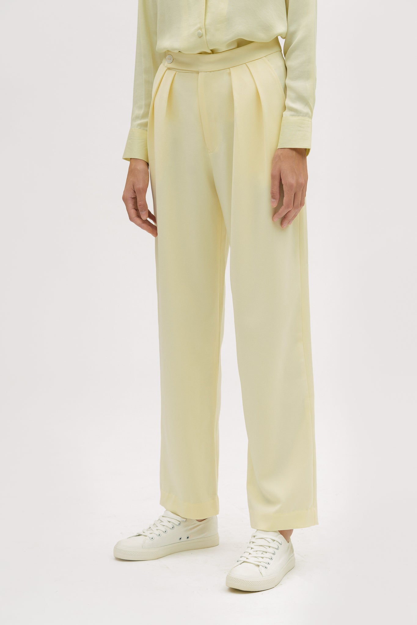 A woman is wearing a yellow shirt and yellow trousers. She is also wearing white tennis shoes.