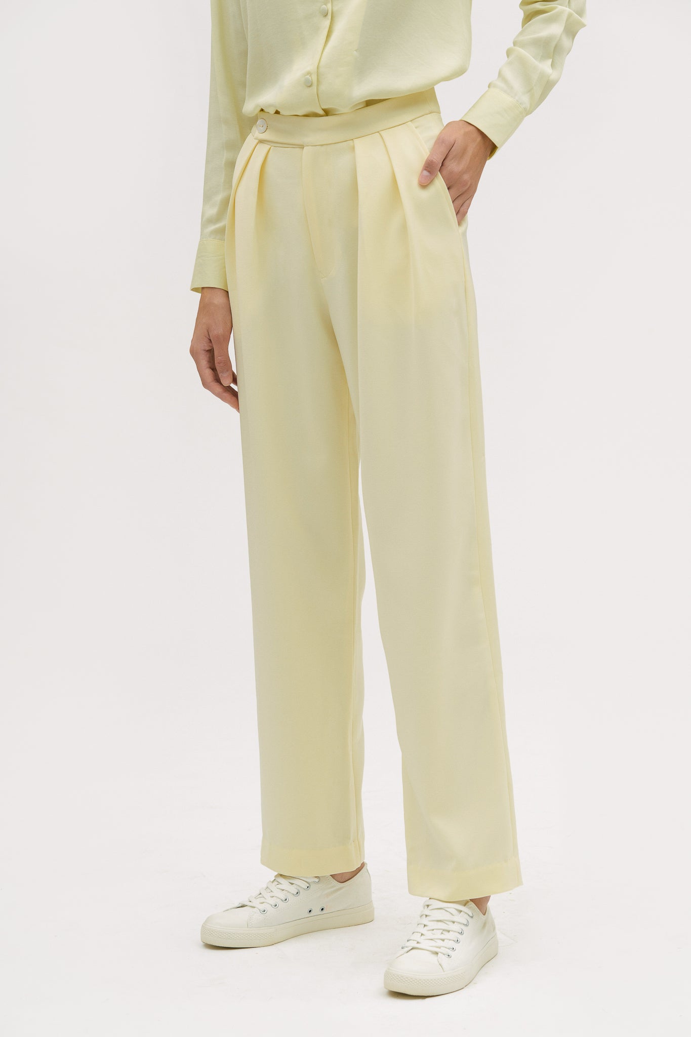 A woman is wearing a yellow shirt and yellow trousers. She is also wearing white tennis shoes.