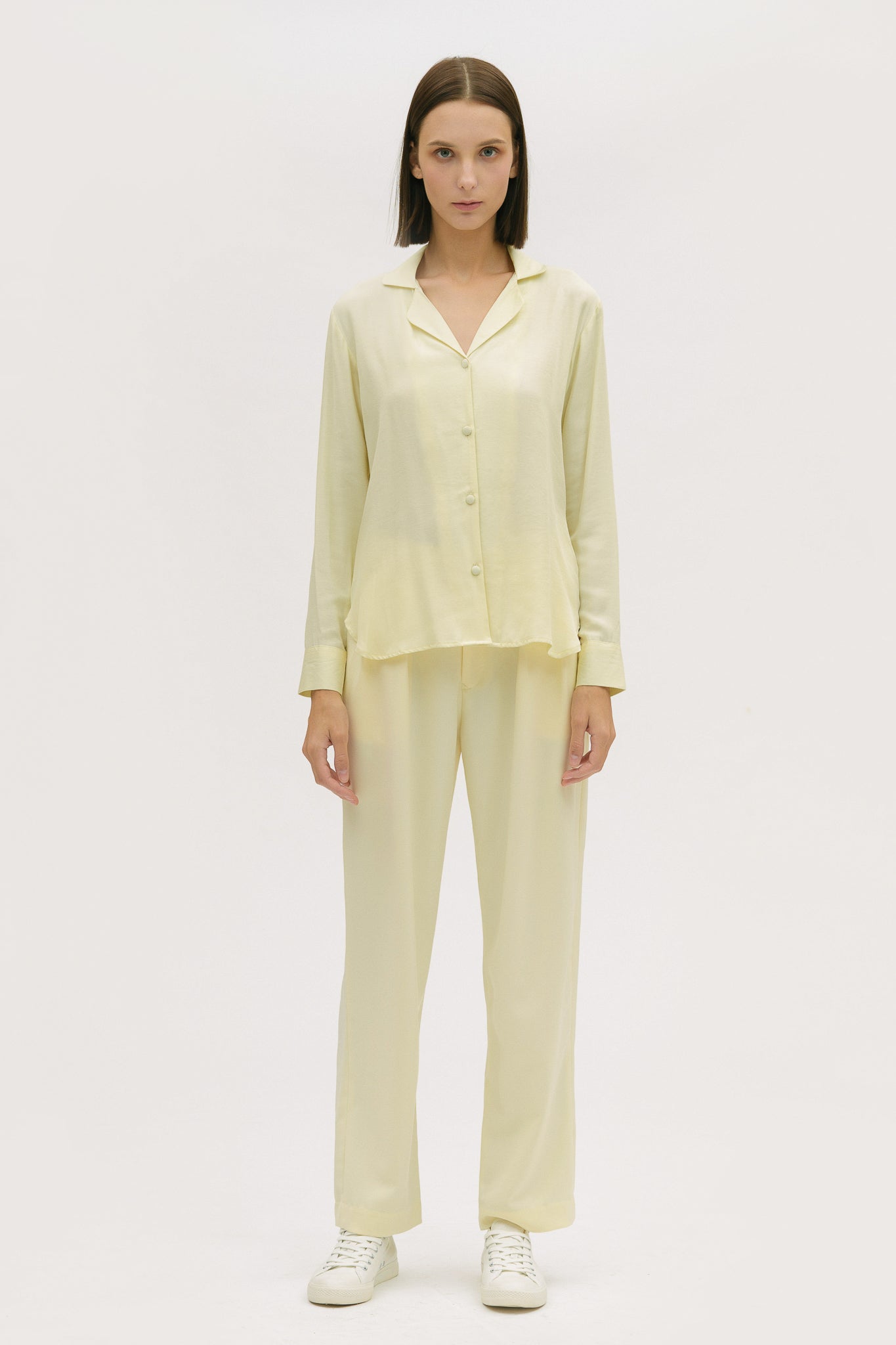 A woman is wearing a lightweight yellow shirt and trousers
