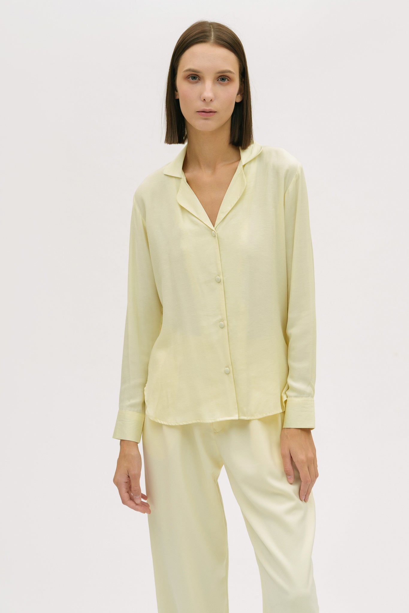 A woman is wearing a lightweight yellow shirt and trousers