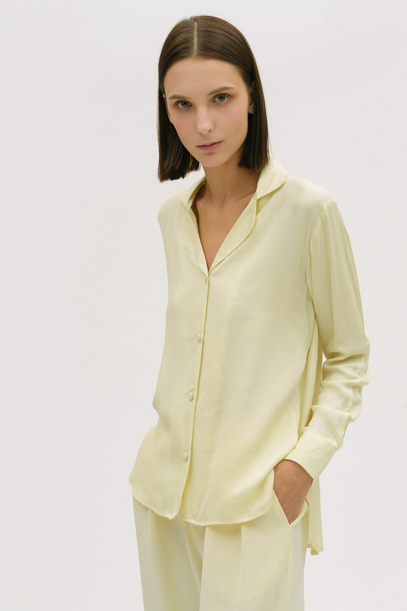 A woman is wearing a lightweight yellow shirt and trousers