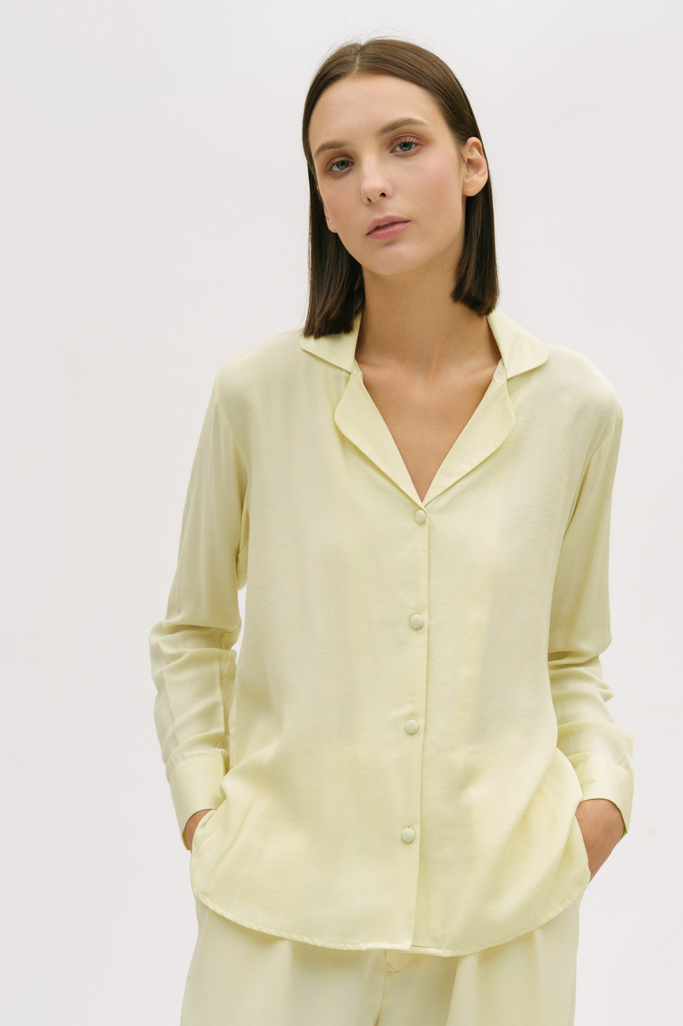 A woman is wearing a lightweight yellow shirt and trousers