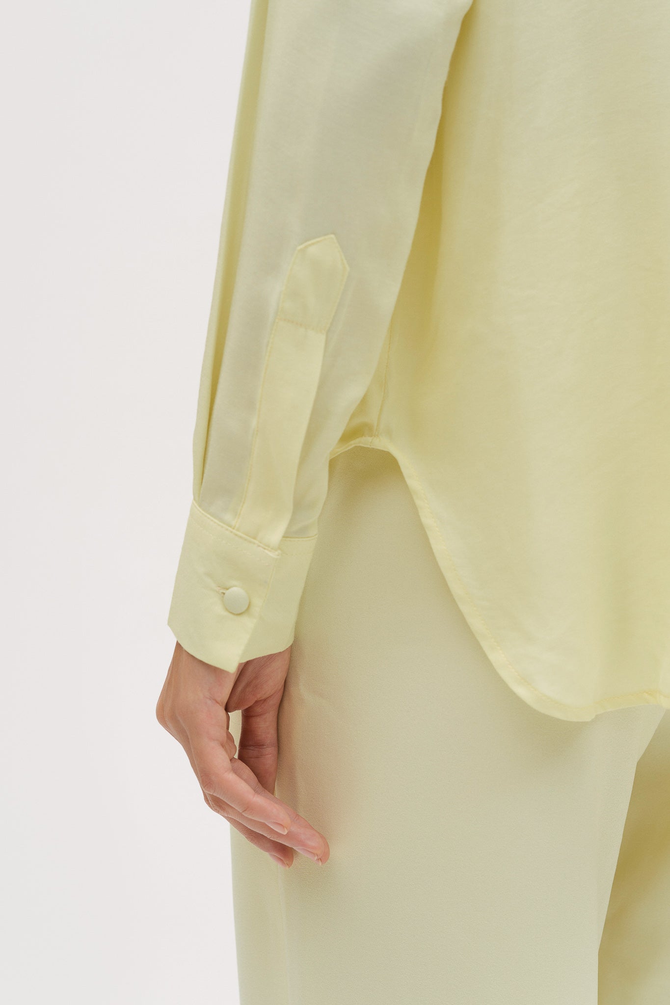 A woman is wearing a lightweight yellow shirt and trousers