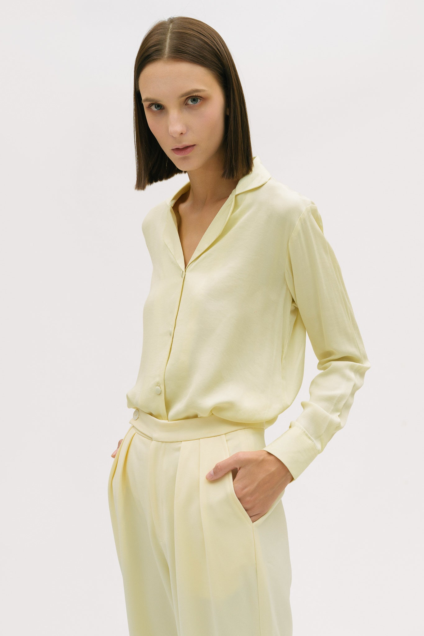 A woman is wearing a lightweight yellow shirt and trousers