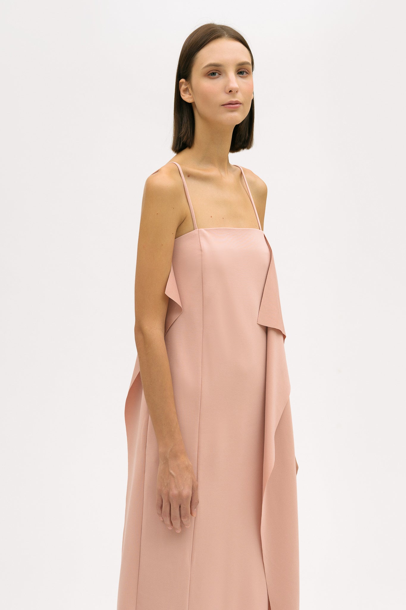 A woman is wearing a pink slip dress with ruffles.