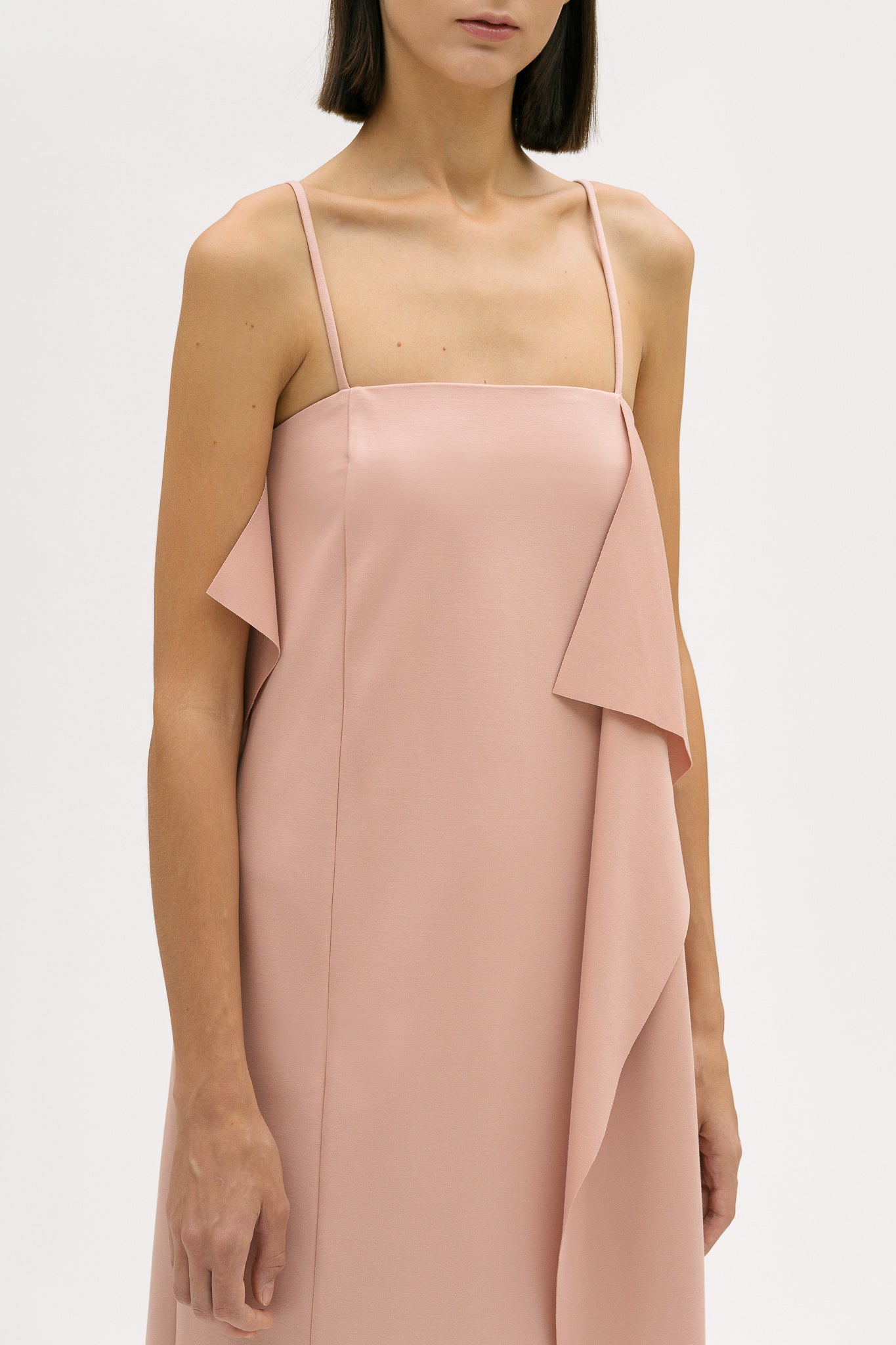 A woman is wearing a pink slip dress with ruffles.