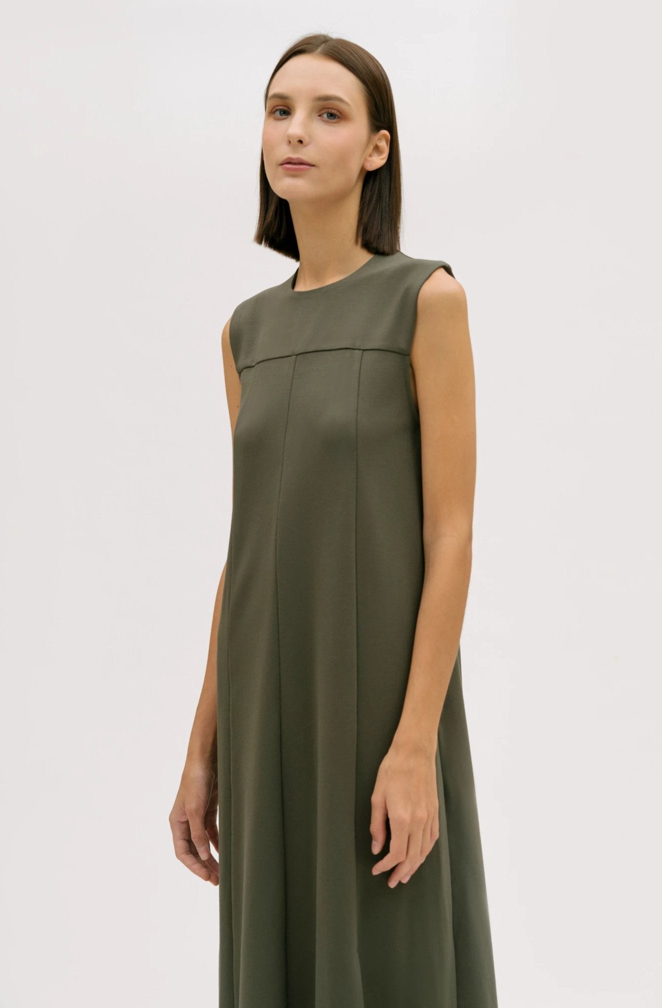 A woman wearing a dusty olive dress.
