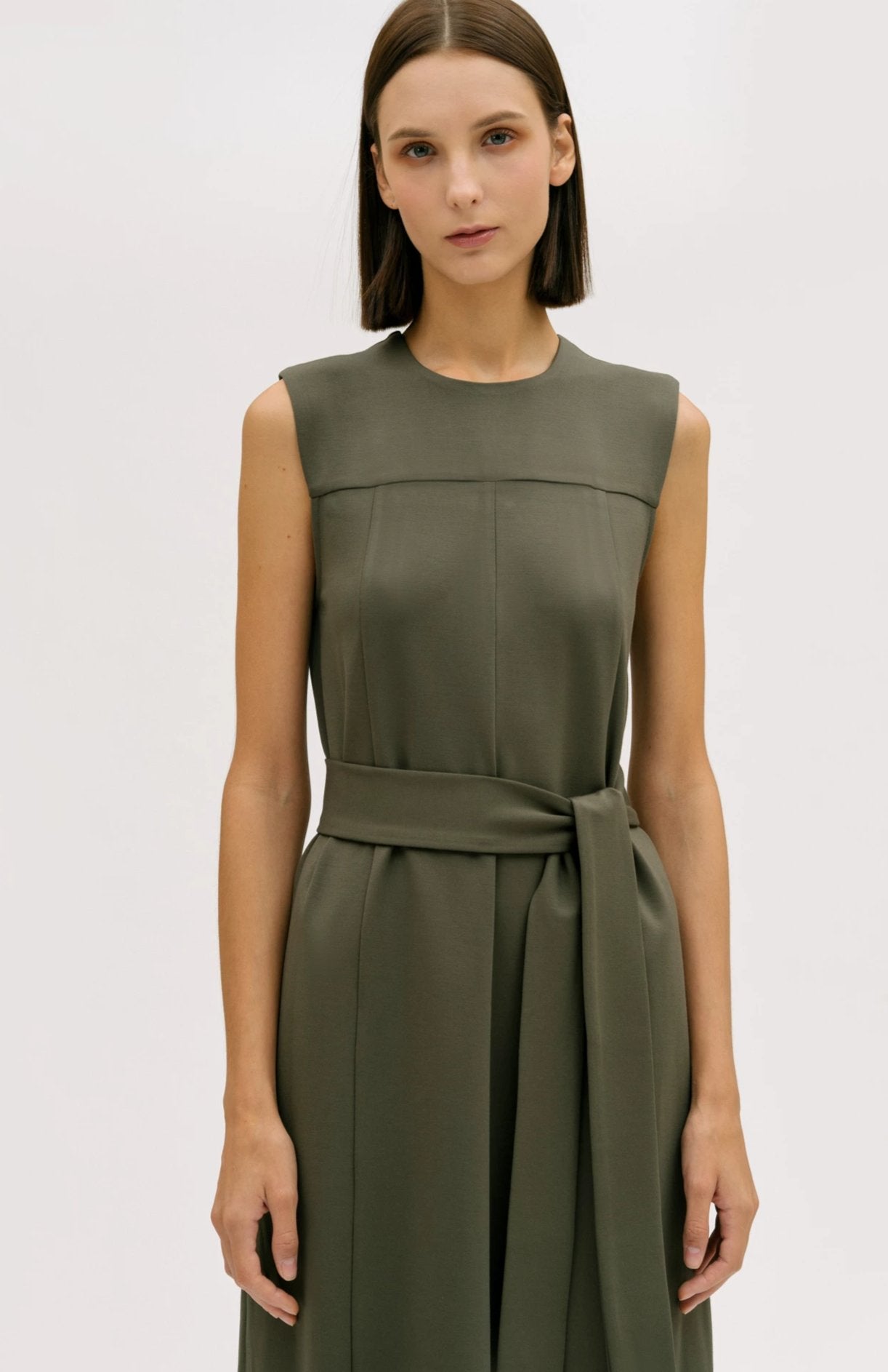 A woman wearing a dusty olive dress.