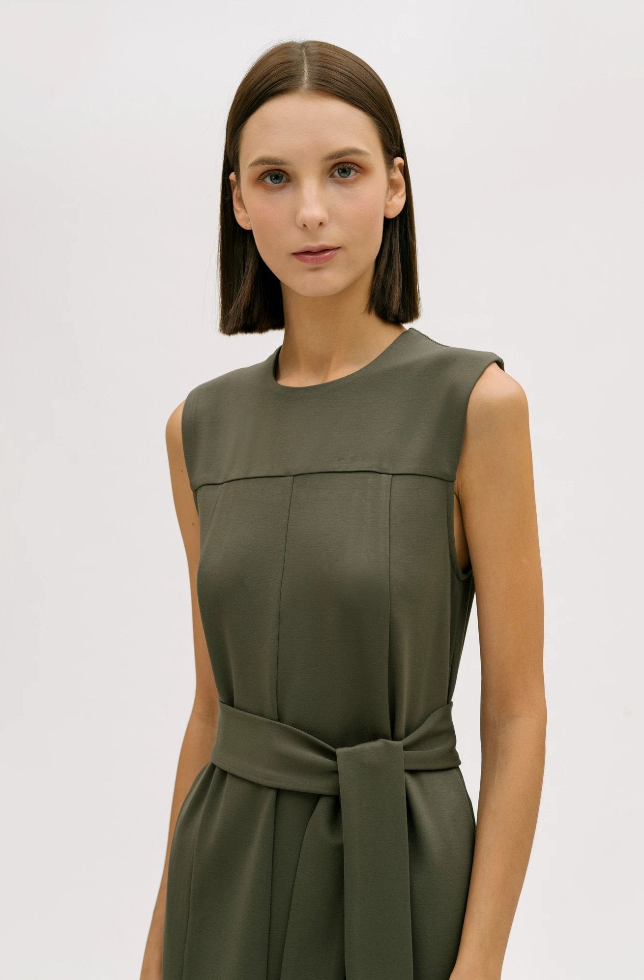 A woman wearing a dusty olive dress.